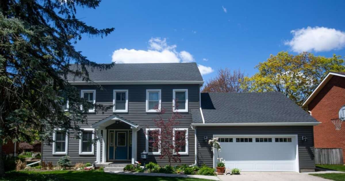 House exterior: Two-story home with dark siding and a manicured lawn.